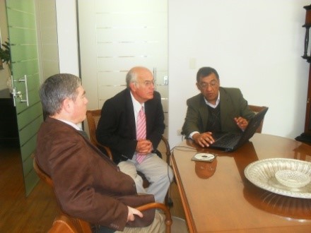 Ramón Zubizarreta and two others sitting around a table during a reunion, looking at a laptop.