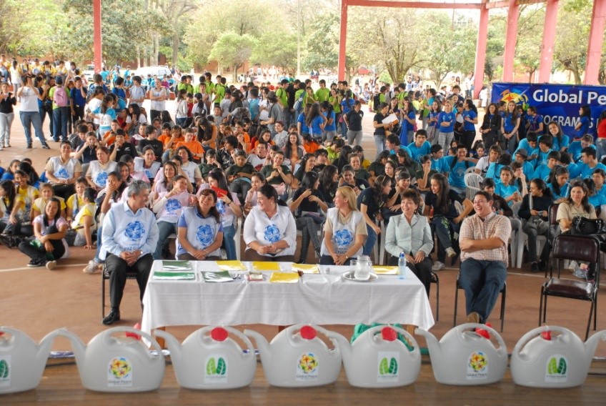A group of people sitting in front of a large group of people, actively participating in an environmental convenio.
