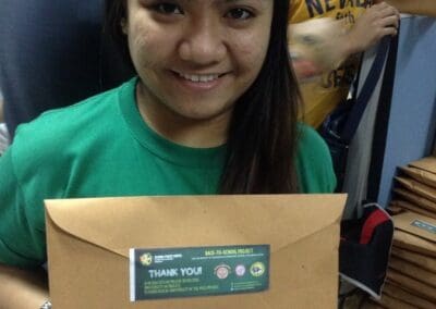Global Peace Foundation volunteer holds back-to-school package.