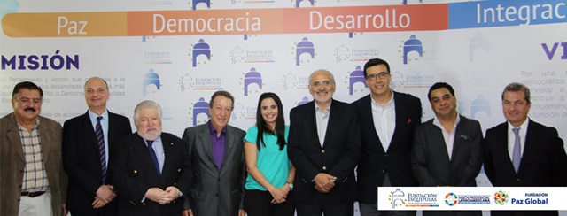 Group of individuals involved in a Latin American Presidential Mission posing for a photo against a backdrop with words 