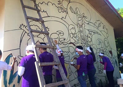 Global Peace Foundation volunteers paint mural on school building.