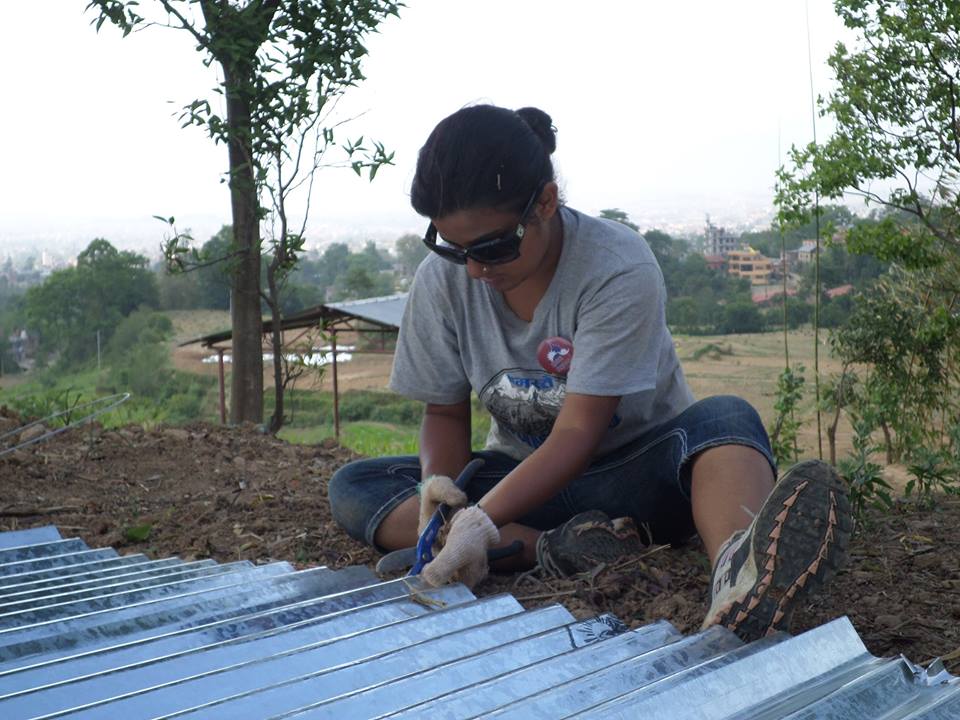 Global Peace Foundation volunteer cuts tin for transitional shelter.