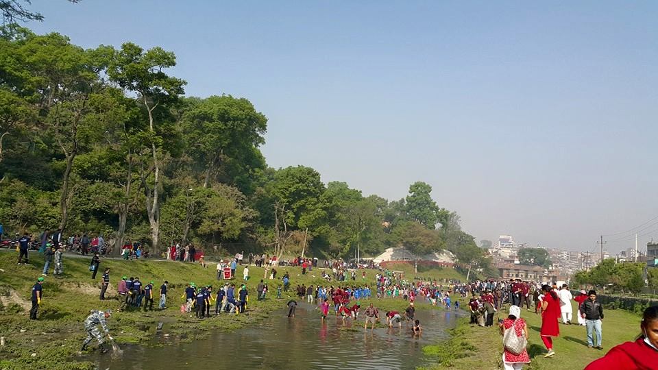 Wide shot of volunteers cleaning the Bagmati River during 100th Week Celebration.