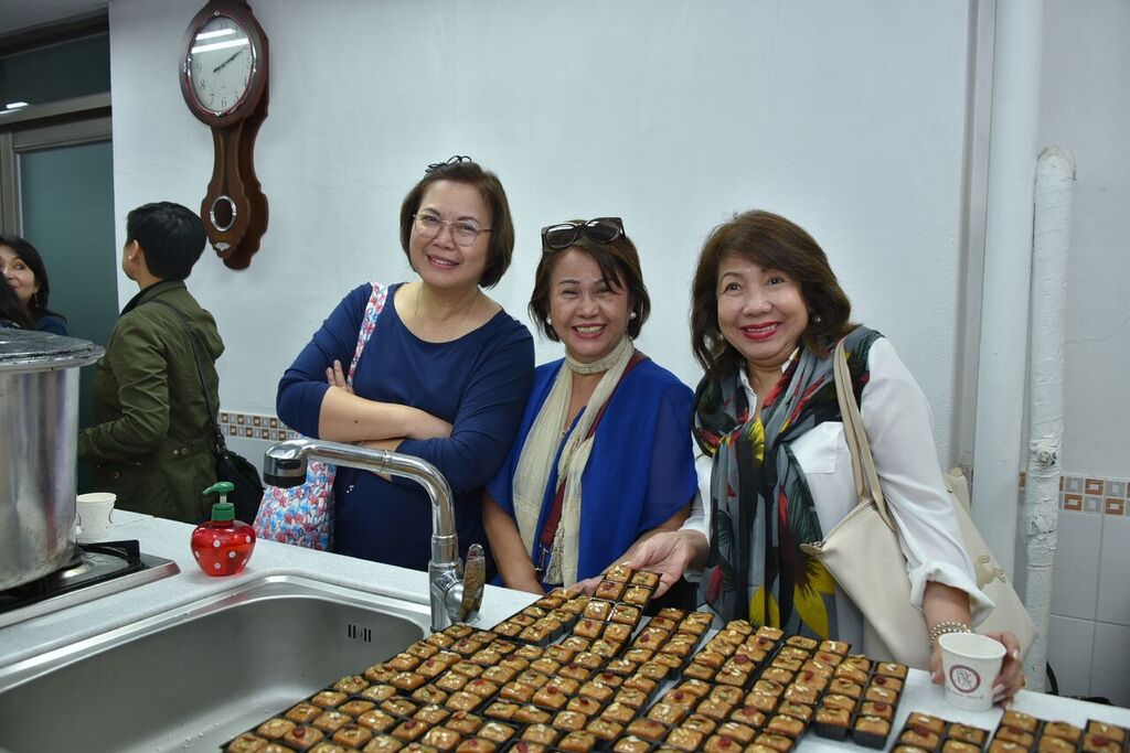 Women leaders pose in front sweets they have made