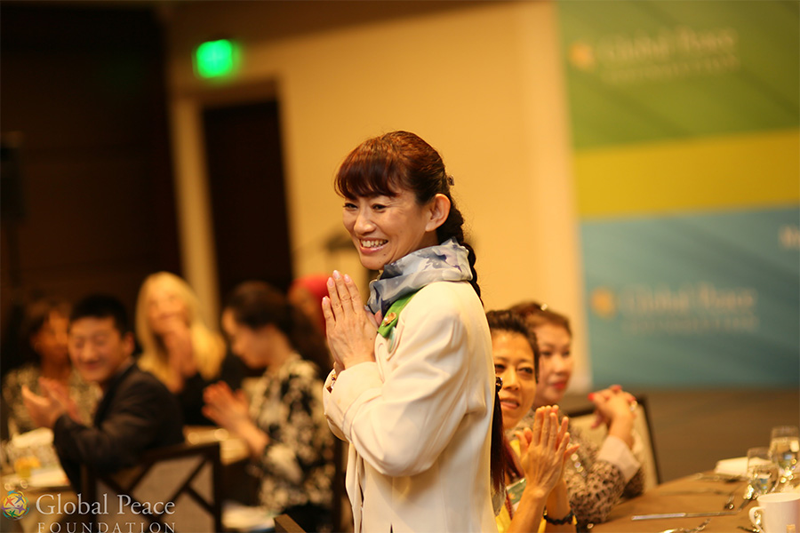 A Japanese actress clapping at a conference.