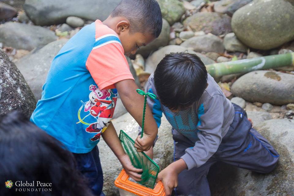 A group of children are playing with a bucket in a river.