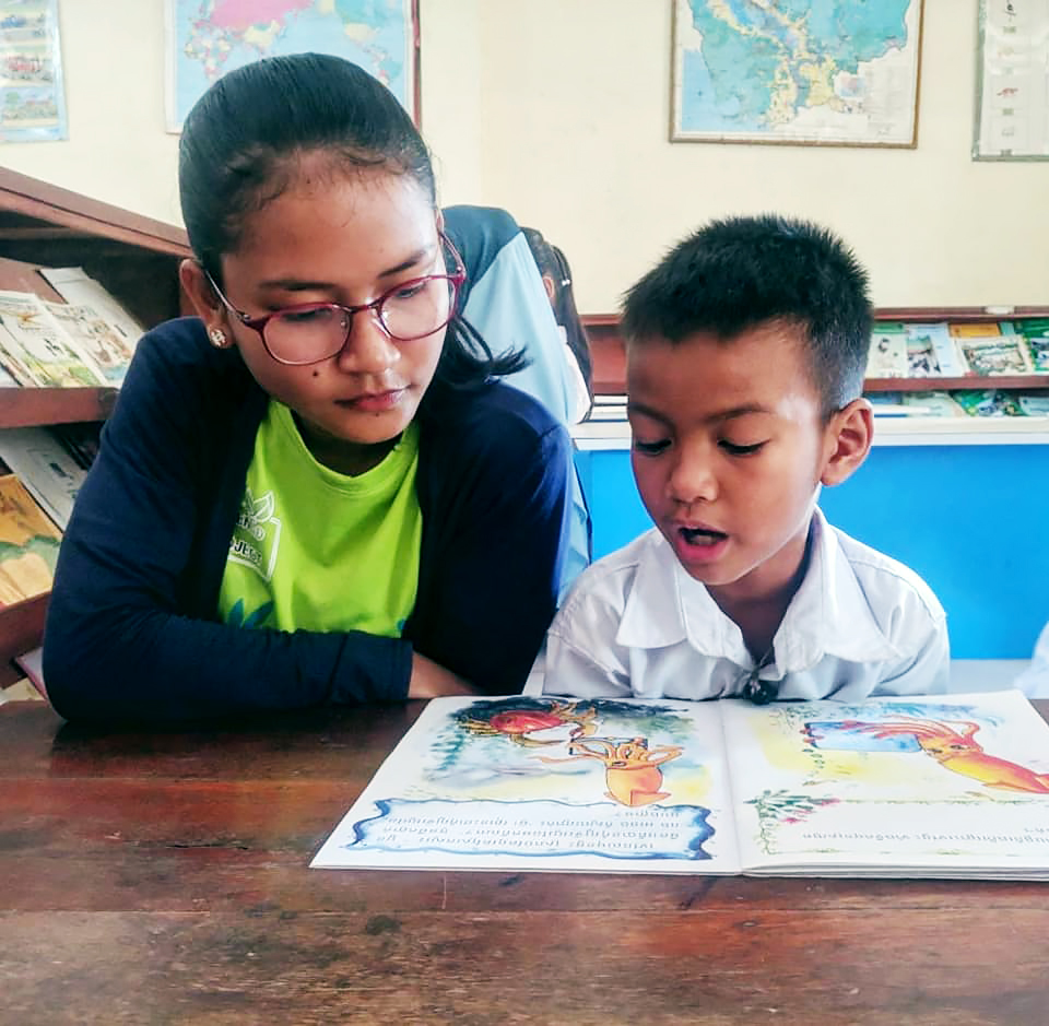 Global Peace Volunteer reads with a young student in Cambodia