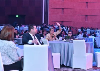 Audience member raising hand to ask a question during a conference event.