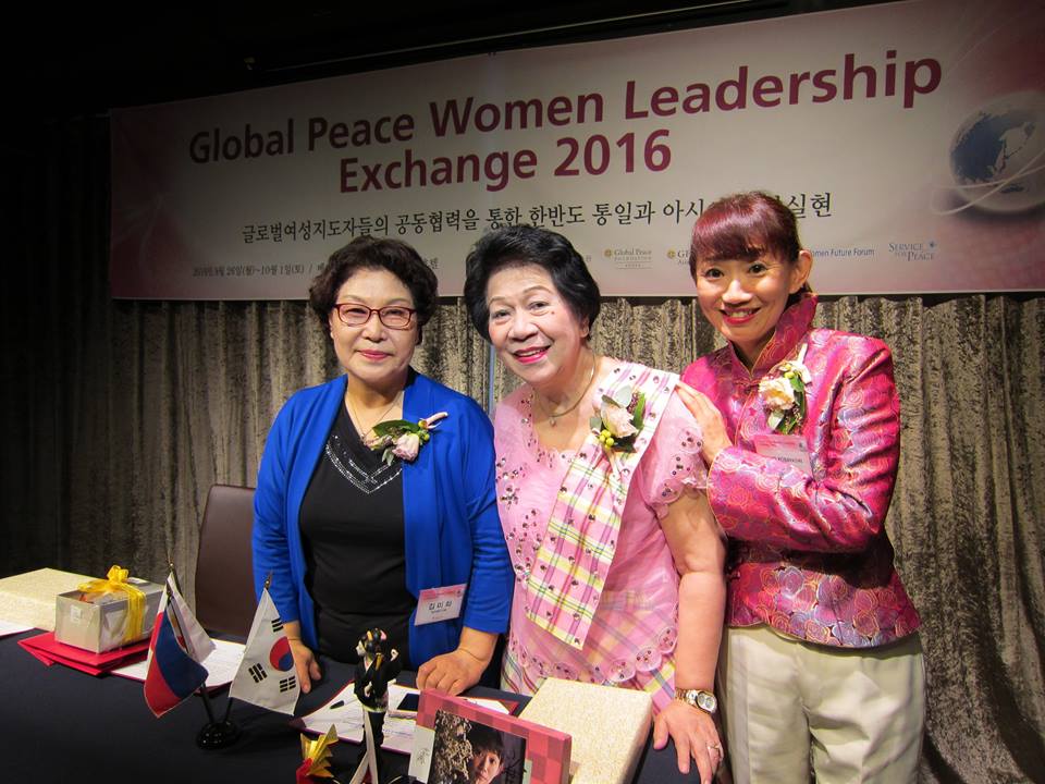 Three women posing with corsages at the global peace women leadership exchange 2016 event.