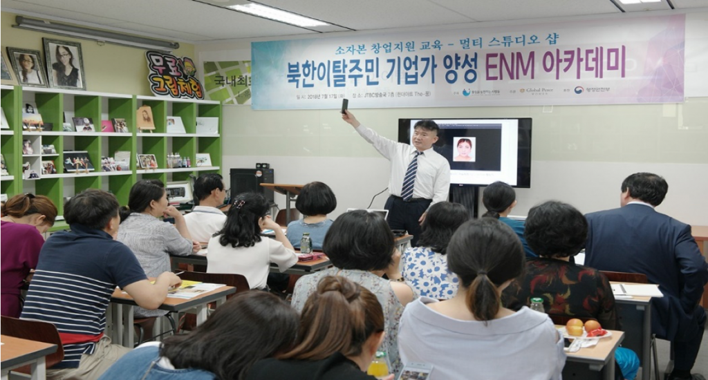 Instructor Joo-wan Kim holds up phone in demonstration to North Korean defectors