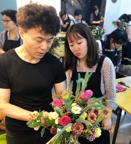 Instructor Myeon Oh assists a student in flower arrangement