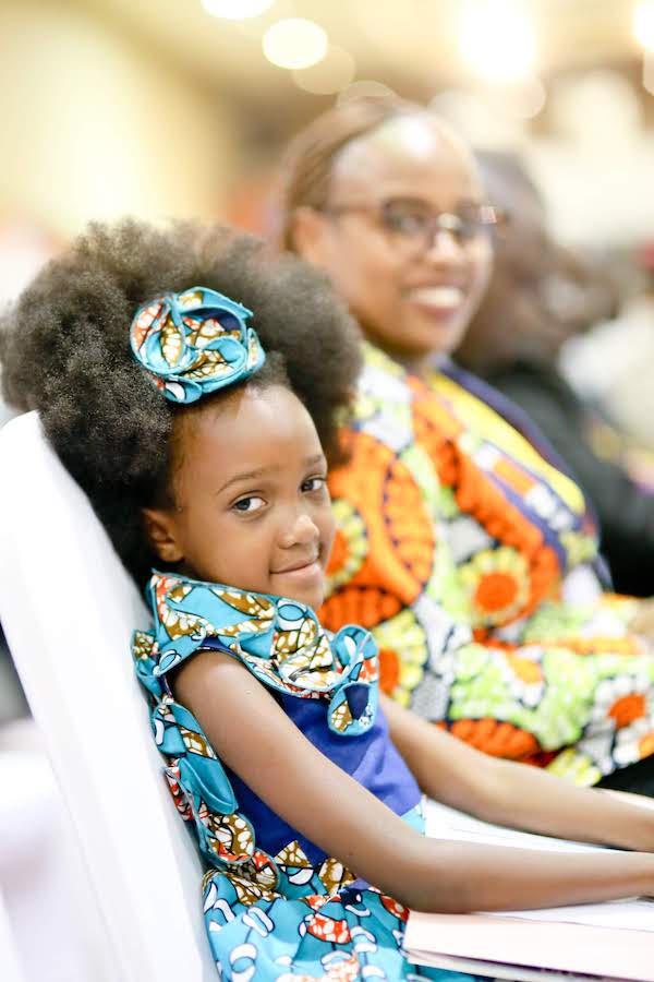 Girl sits next to her mother at the 2018 Global Peace Leadership Conference held in Uganda