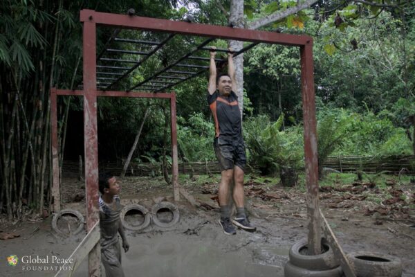 A man doing a pull up in the jungle.