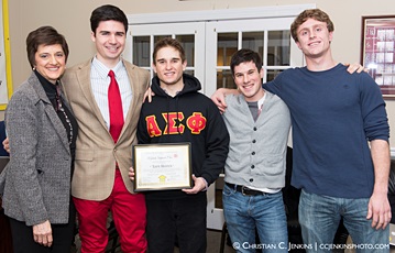 Five people smiling for a photo, one holding a framed certificate.