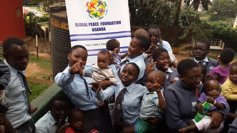 A group of childern gather around a Global Peace Foundation sign in Uganda