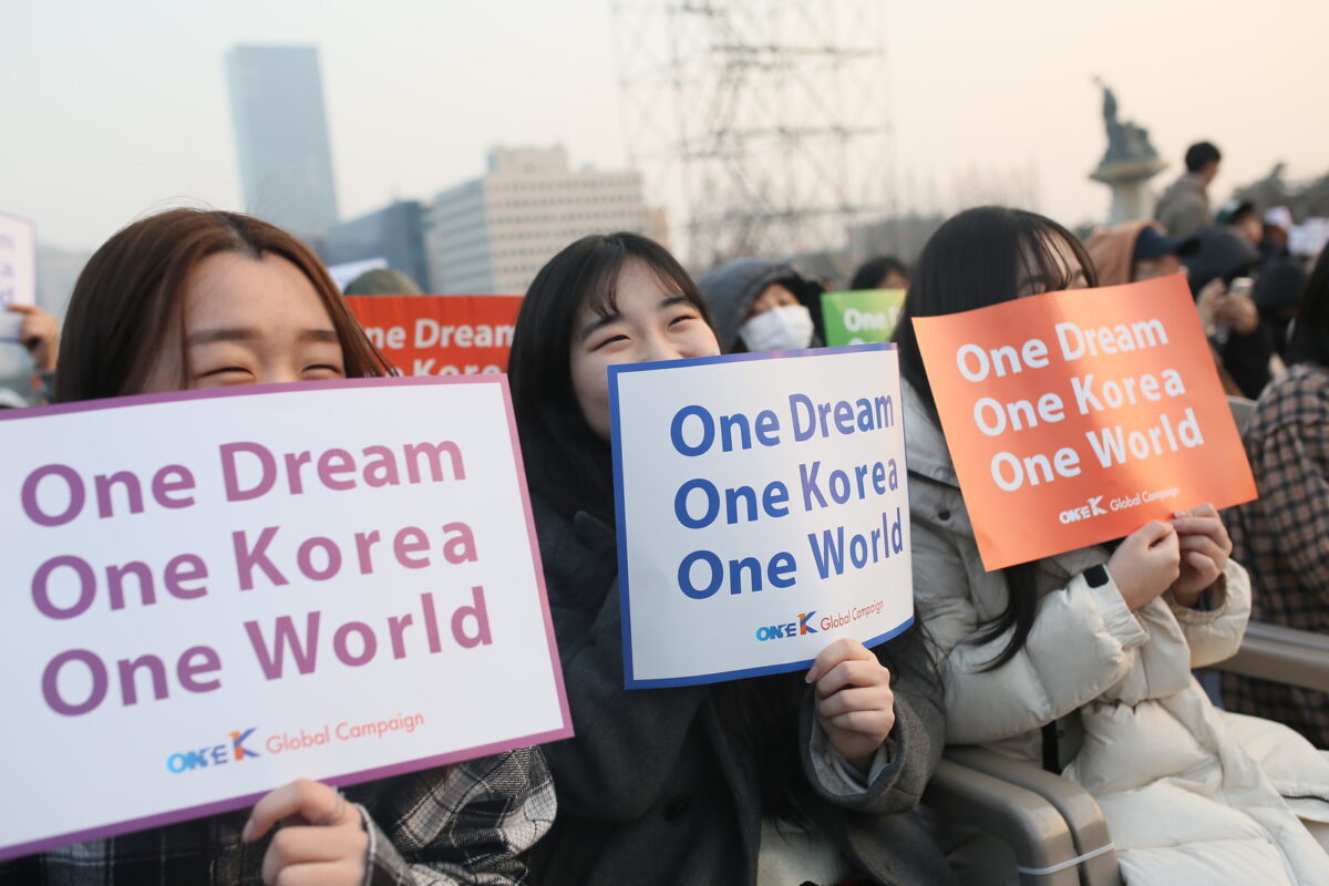A group of people holding signs that say one dream one korea world.