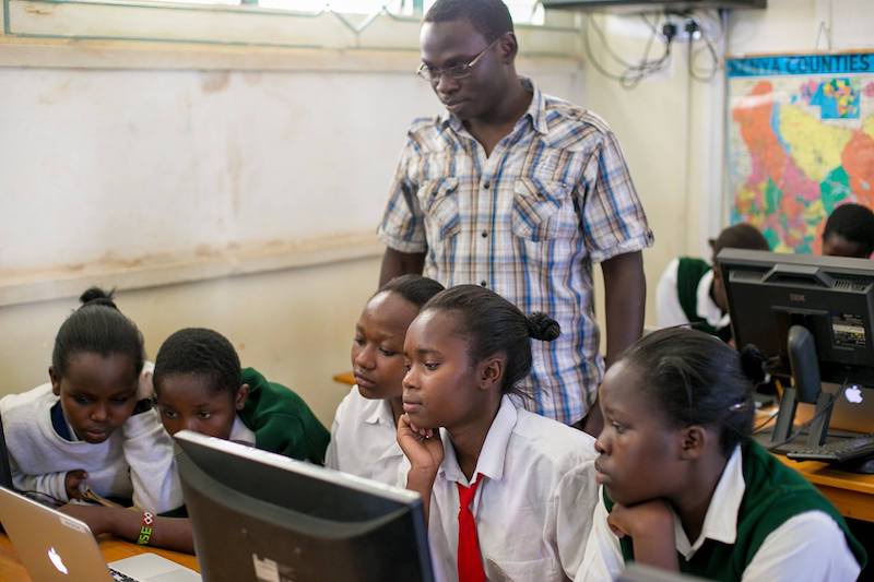 Teacher with students around a computer