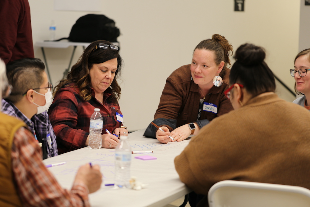 The 2022 Program launches its Cross Community Reconciliation Project, bringing together a group of people sitting around a table.