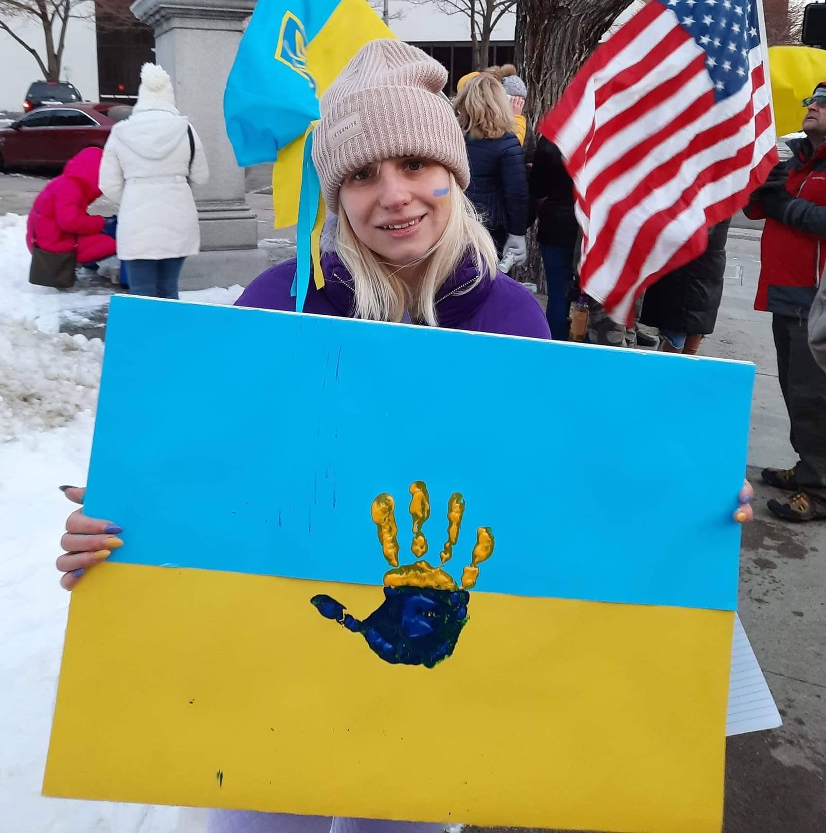 Yuliya holding a sign "Pray for Ukraine"