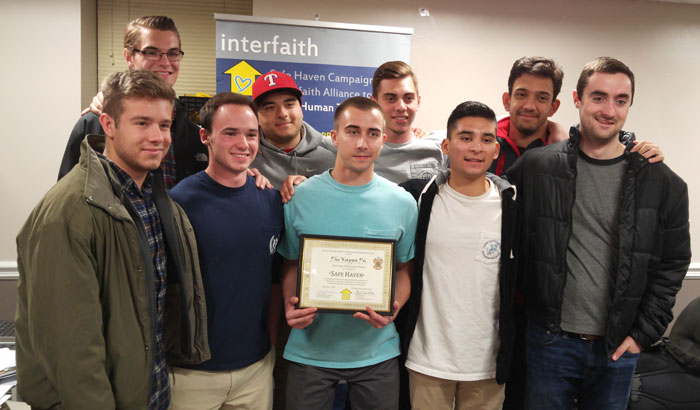 A group of young men smiling for a photo, with one holding an award certificate.