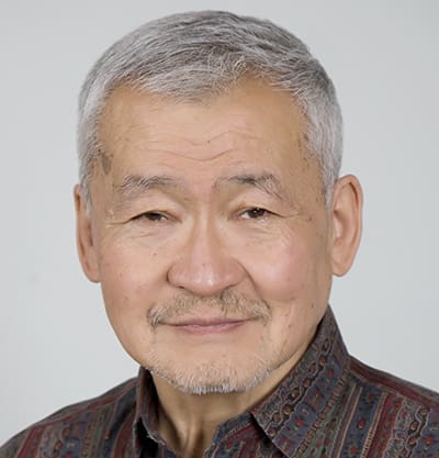 Amb. J. Enkhsaikhan Dr. Jargalsaikhan Enkhsaikhan, an older man with short gray hair and a trimmed mustache and beard, wears a patterned shirt while posing in front of a plain light background.