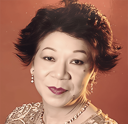 Nona Ricafort Dr. Nona S. Ricafort, a woman with short, styled dark hair, wearing earrings, a necklace, and a patterned top, poses in front of a warm, reddish-brown background.