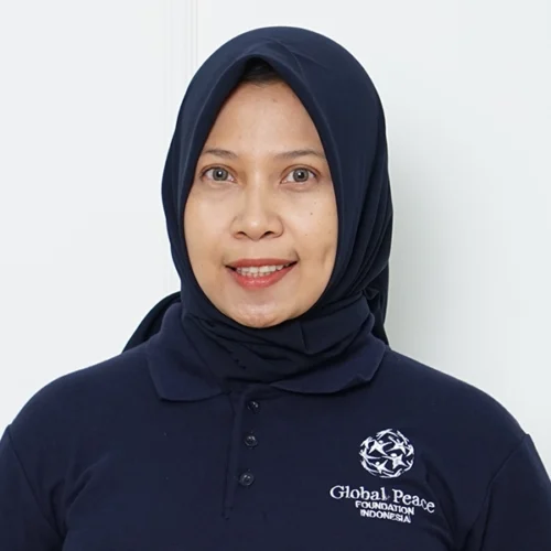 Shintya Rahmi Utami, wearing a navy blue hijab and a "Global Peace Foundation Indonesia" polo shirt, stands against a plain white background.