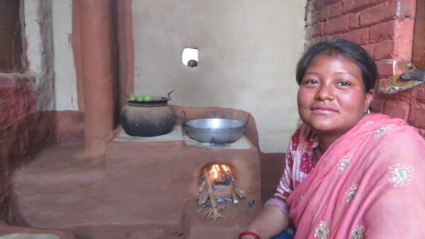 A woman in a sari sitting in front of a stove.