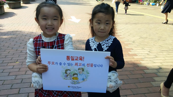 Korean children pose with Unification Education in the Family poster