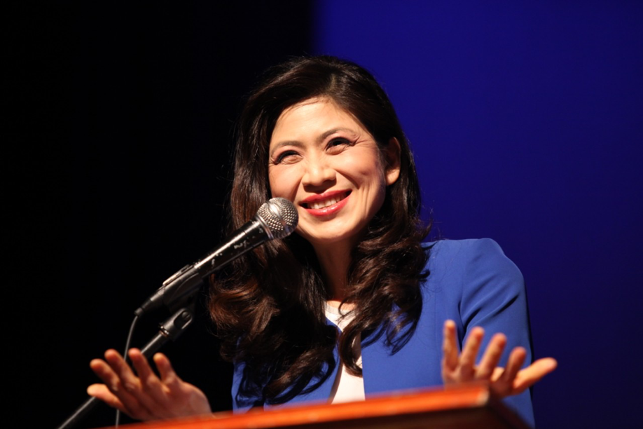 A woman giving a speech into a microphone.