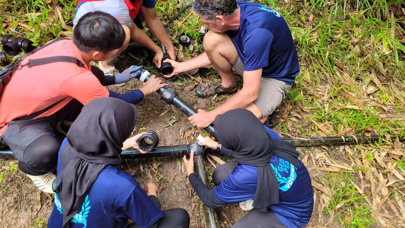 Volunteers connecting a water pipe system