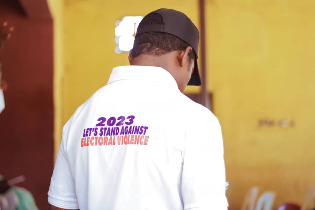 Person displays the back of their shirt that reads "2023 Let's Stand Against Electoral Violence"