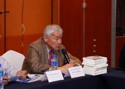 Ambassador Jargalsaikhan Enkhsaikhan discussing Mongolia's role in peacebuilding at a table with microphones and books.