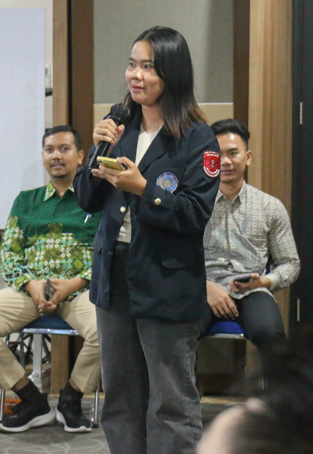 A woman is delivering a speech at a GPF Indonesia-hosted seminar, emphasizing Pancasila and global peace.