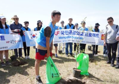 A group of people from Mongolia planting trees in front of a group of people.