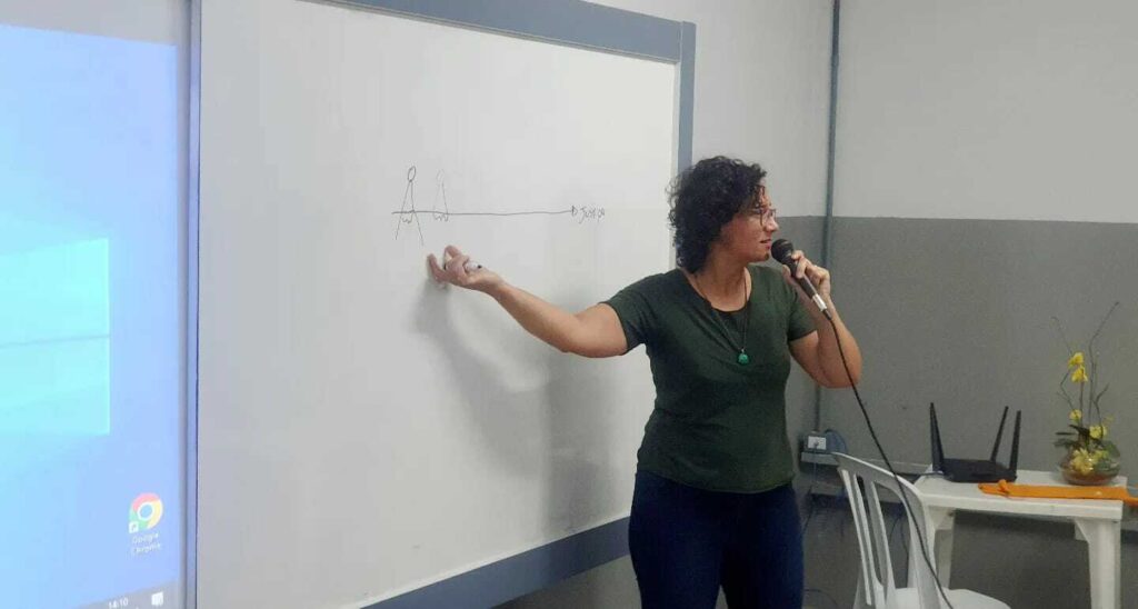 A woman delivering a presentation in front of a whiteboard for Conversations that Connect: Brazil Program.