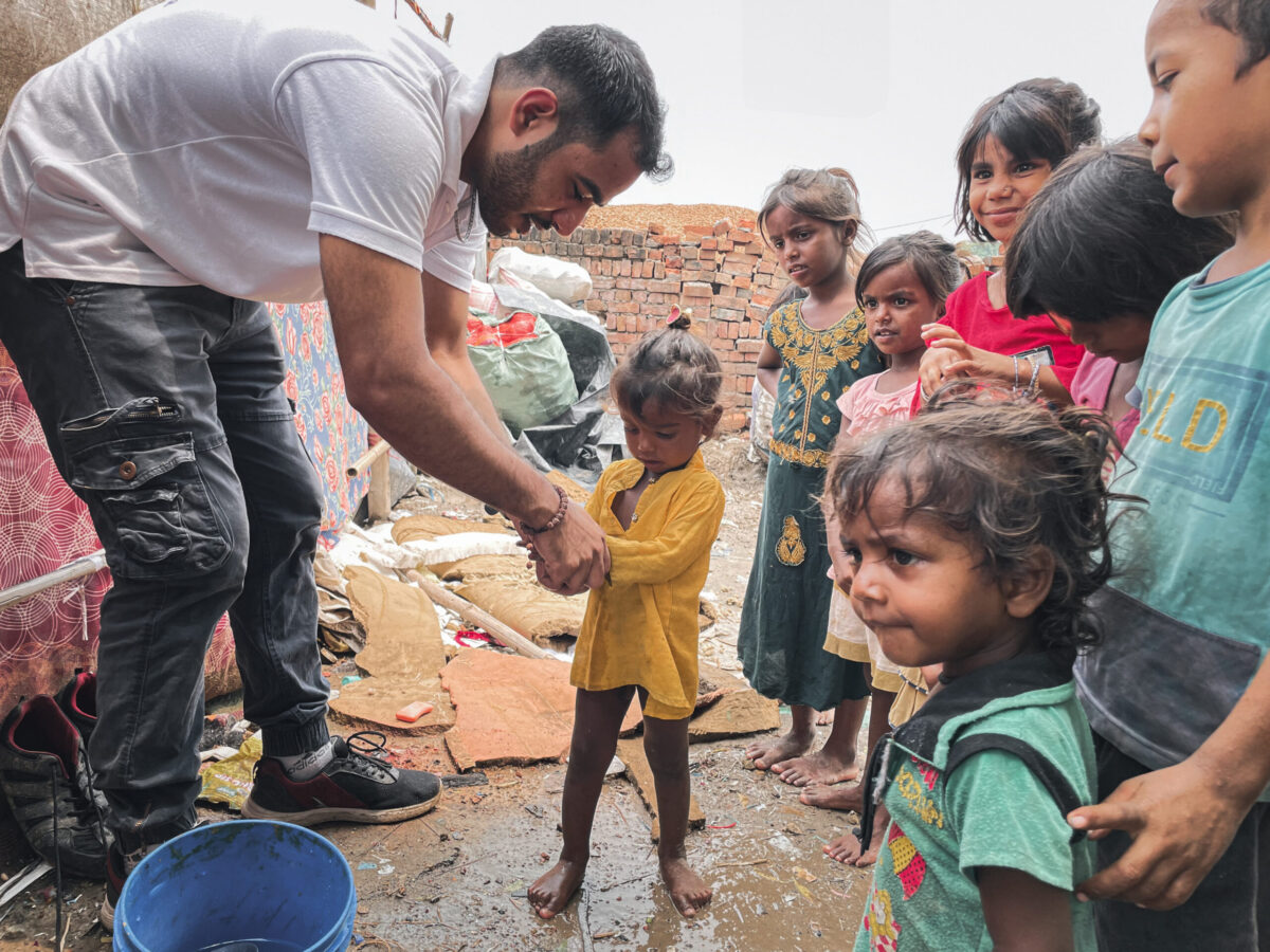 A man is offering water to a group of children.
