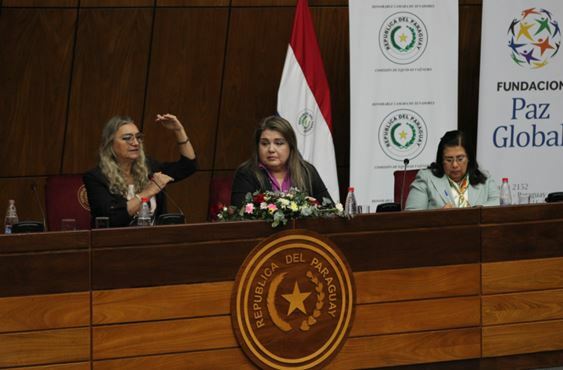 Women participating in the Paraguay National Forum for the Protection of Women sit at a podium.