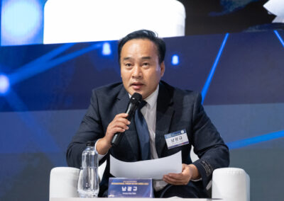 A man in a suit is speaking into a microphone at the International Forum on One Korea 2023 held in Seoul.