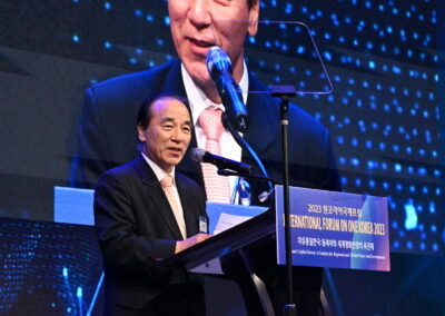 A man in a suit standing at a podium during the International Forum on One Korea 2023 held in Seoul.