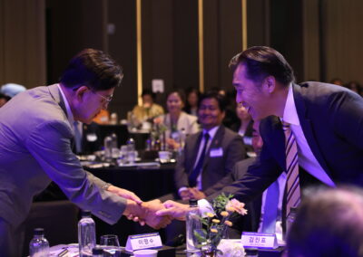A man in a suit shaking hands with another man at the International Forum on One Korea 2023 held in Seoul.