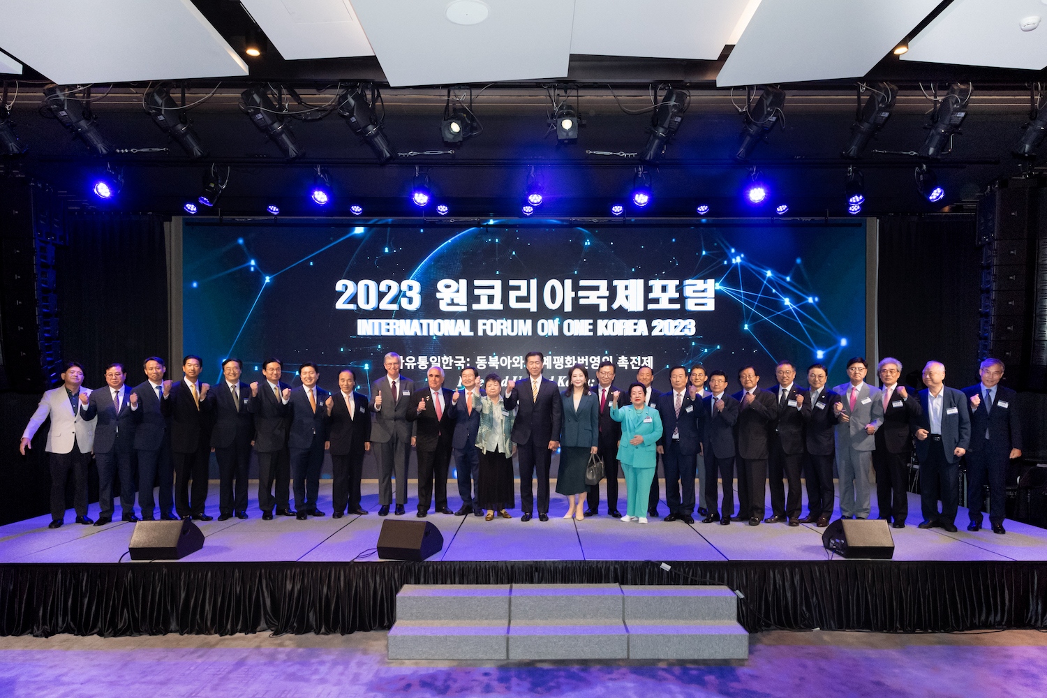A group of people standing on stage at the International Forum on One Korea 2023 held in Seoul.