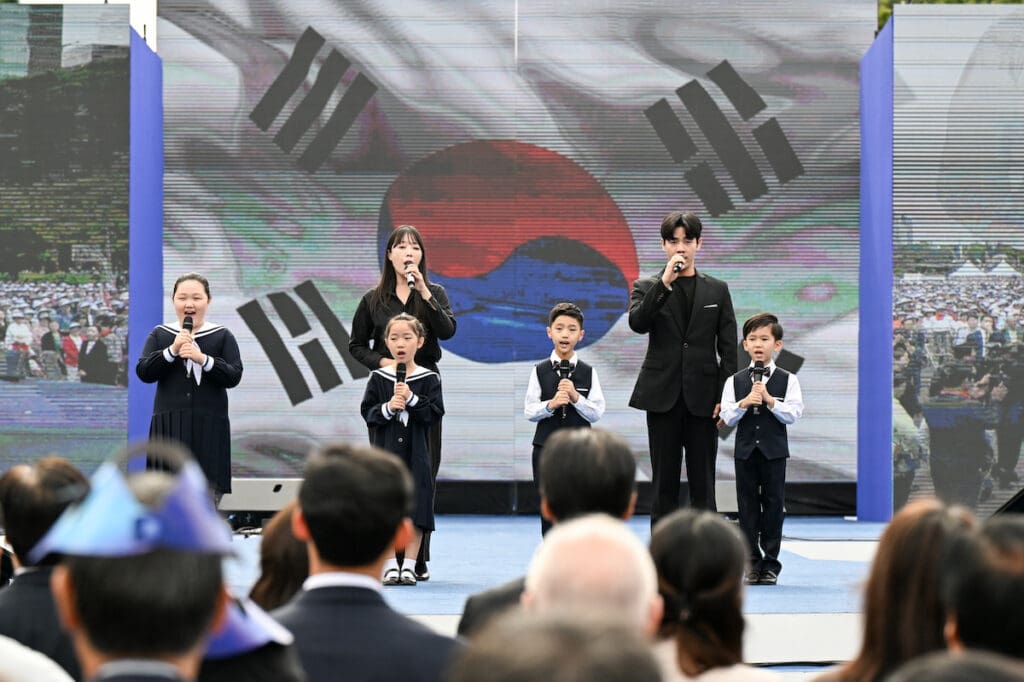 A group of people standing in front of a screen with a korean flag.