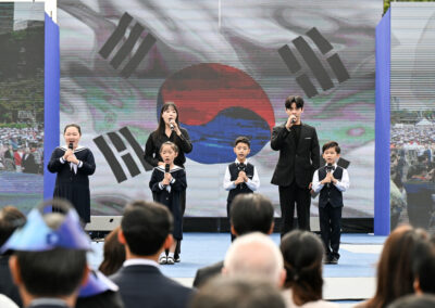 A group of people standing in front of a screen with a korean flag.