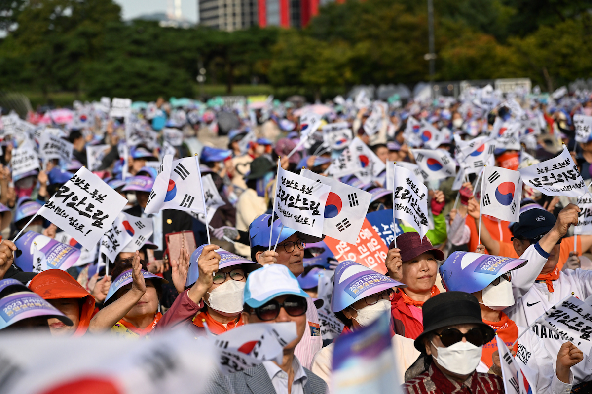 A group of people holding signs with korean flags.