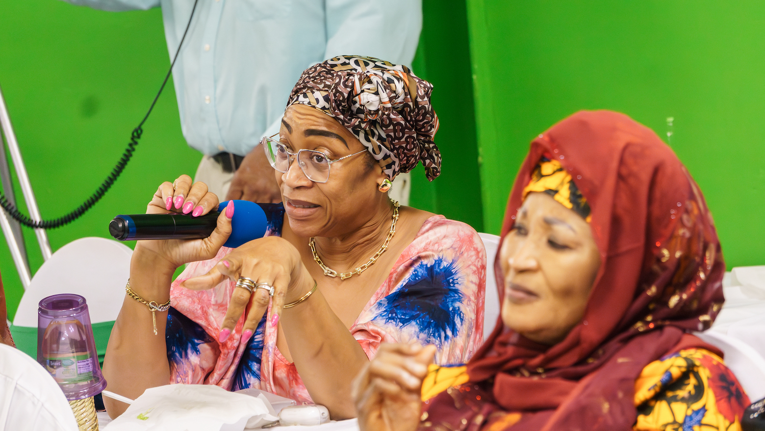 A woman in a head scarf is speaking into a microphone at the GPF USA's Community Safety Awareness Trainings.