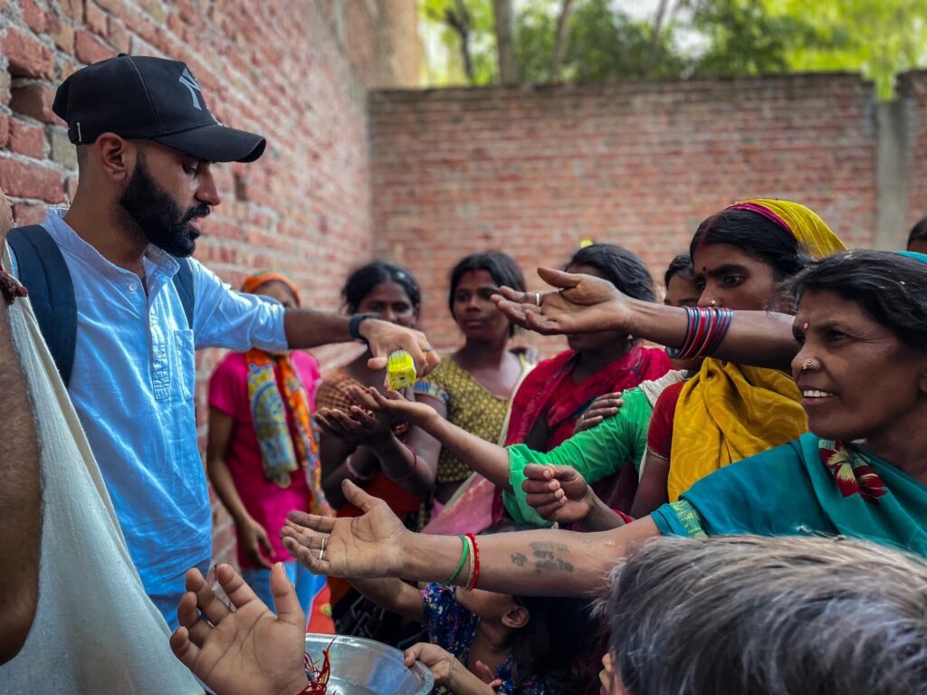 A man is inspiring youth through service by handing out food to a group of people in India.