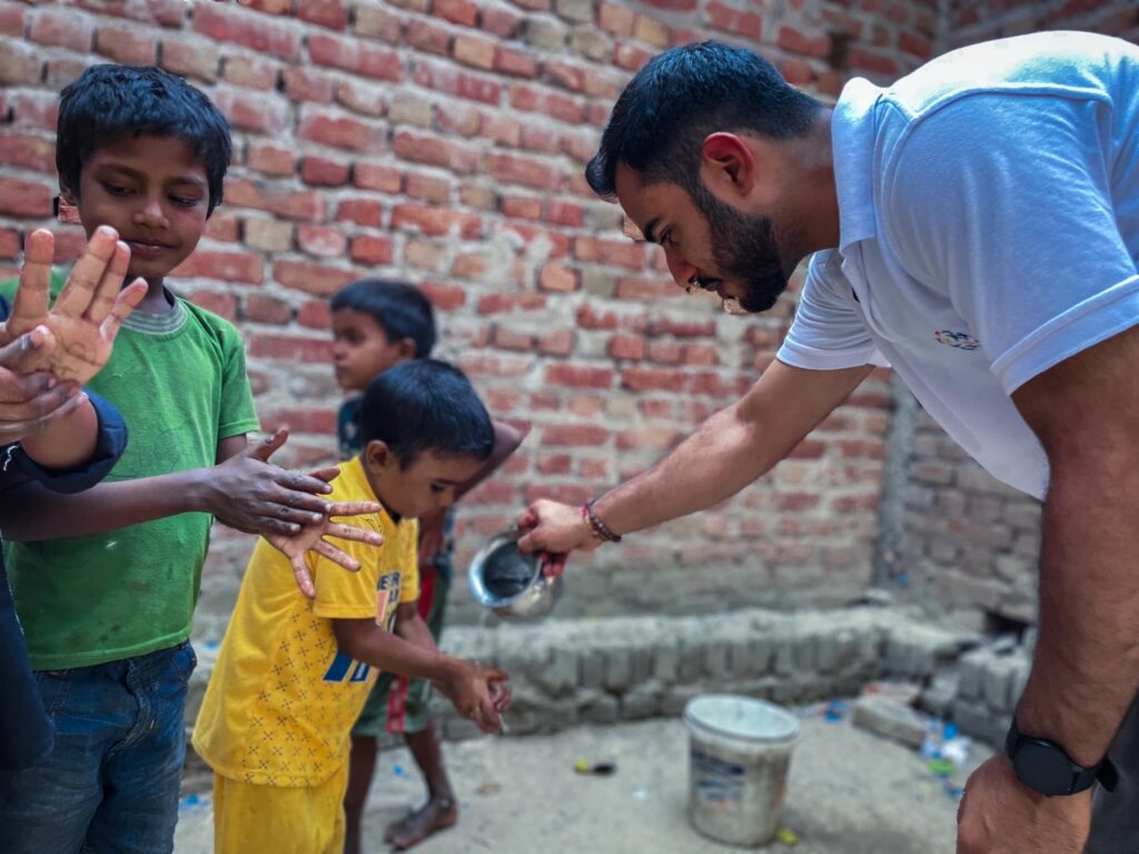 A man is giving a hand to a group of children in India's youth programs.