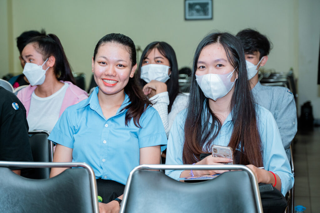 A group of youth students engaging in peacebuilding exercises while wearing face masks in a classroom.