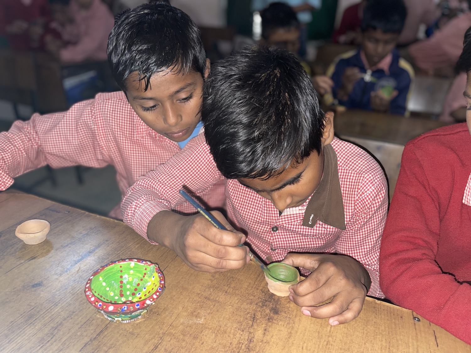 A group of children are working on a table in a classroom during the Festival of Lights, Diwali.
